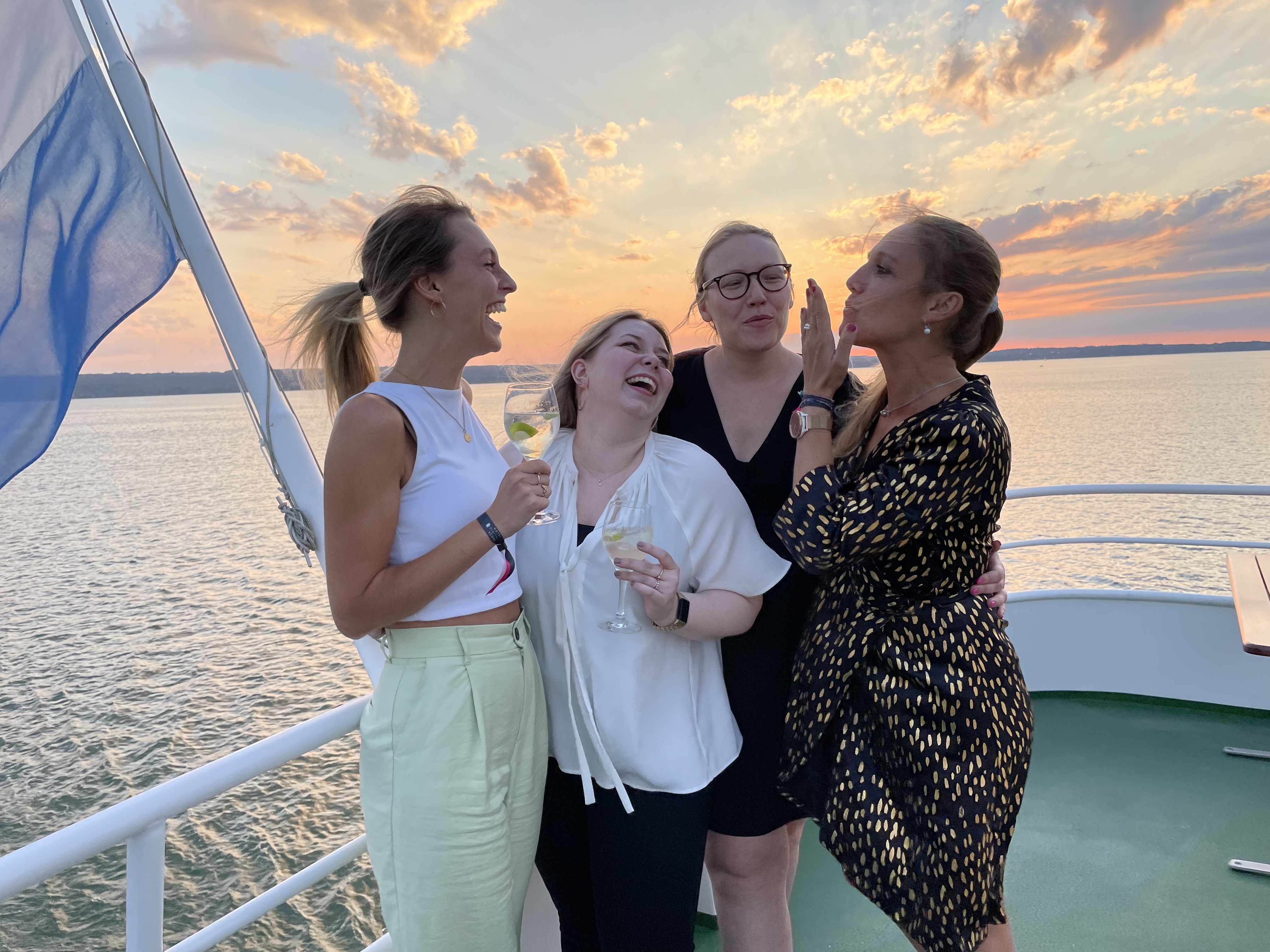 Vier Online Birds Mitarbeiterinnen die bei einer Schiffsfahrt lachend nebeneinander stehen