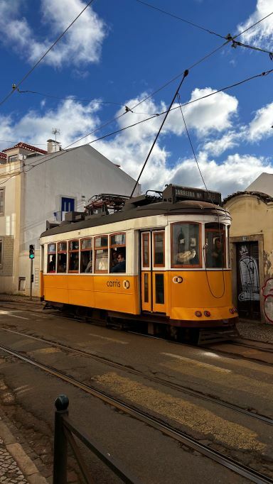 Gelbe Straßenbahn in Lissabon, die gerade an einer Haltestelle steht