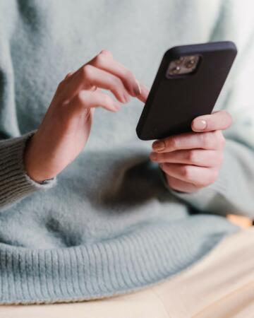 Frau tippt auf einem IPhone mit einer schwarzen Hülle