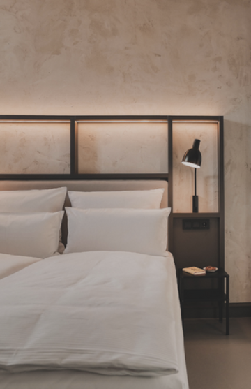 Modernes gemütlich beleuchtetes Hotelbett mit weißem Bezug