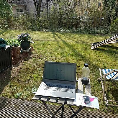 Kleiner Tisch im Garten mit einem Laptop