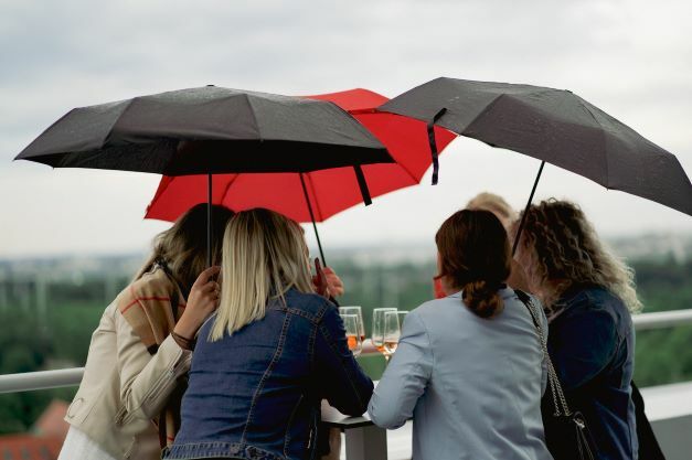 Online Birds Mitarbeiterinnen die am Strategy Day mit Regenschirmen um einen Tisch herum stehen